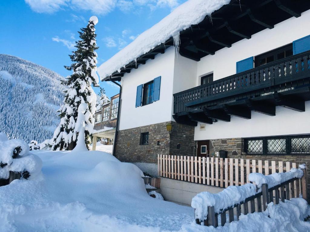 Villa Emilia في كالز ام غروغلوكنير: منزل مغطى بالثلج مع شجرة عيد الميلاد