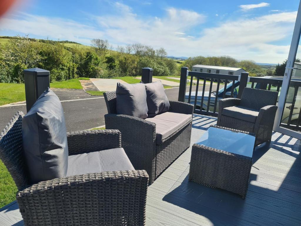 a porch with wicker chairs and a couch and a table at Mawgan Pads Padstow in Padstow