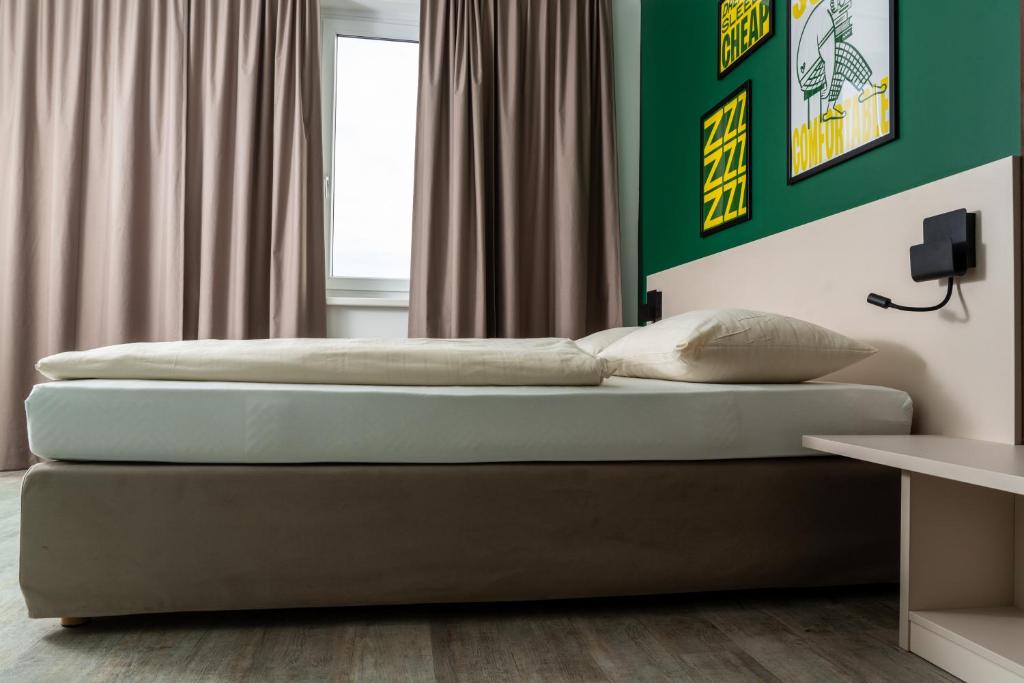 een slaapkamer met 2 bedden en een groene muur bij SLEEEP HOTEL Ansfelden in Linz