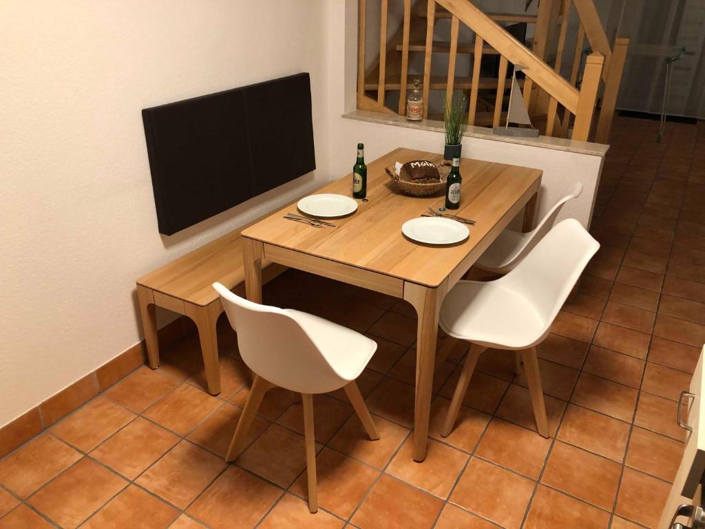 einen Holztisch mit weißen Stühlen und einen TV in der Unterkunft Ferienhaus Segelbär in Hooksiel