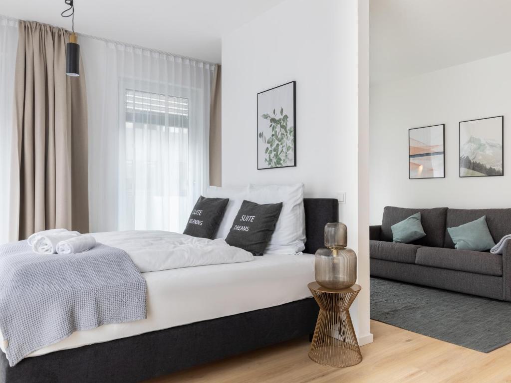 a white bedroom with a bed and a couch at limehome Gütersloh Eickhoffstraße in Gütersloh