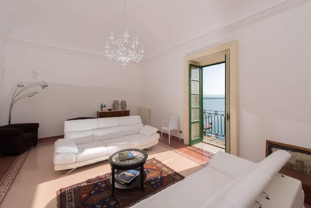 a living room with white furniture and a large window at DUOMO SEA SIDE DELUXE APARTMENT by Ortigiaapartments in Siracusa