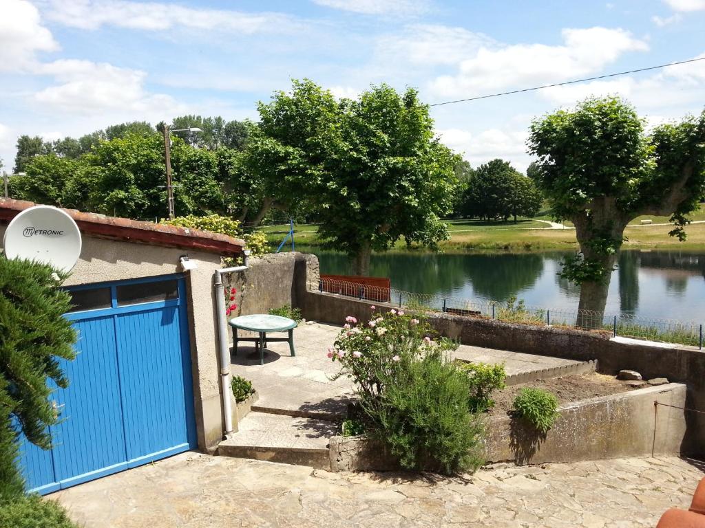 a blue garage door in front of a lake at Le Gîte du Port in Saint-Pierre-de-Boeuf