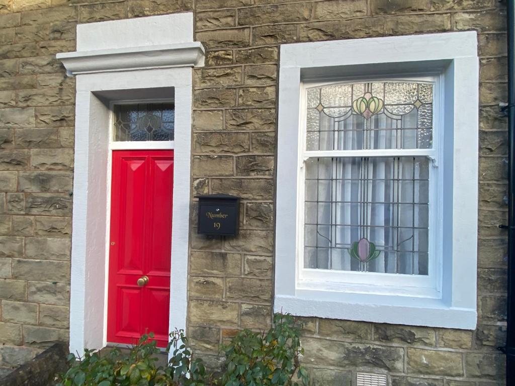 a red door and a window on a brick building at Number 19 - Victorian Town House in Clitheroe