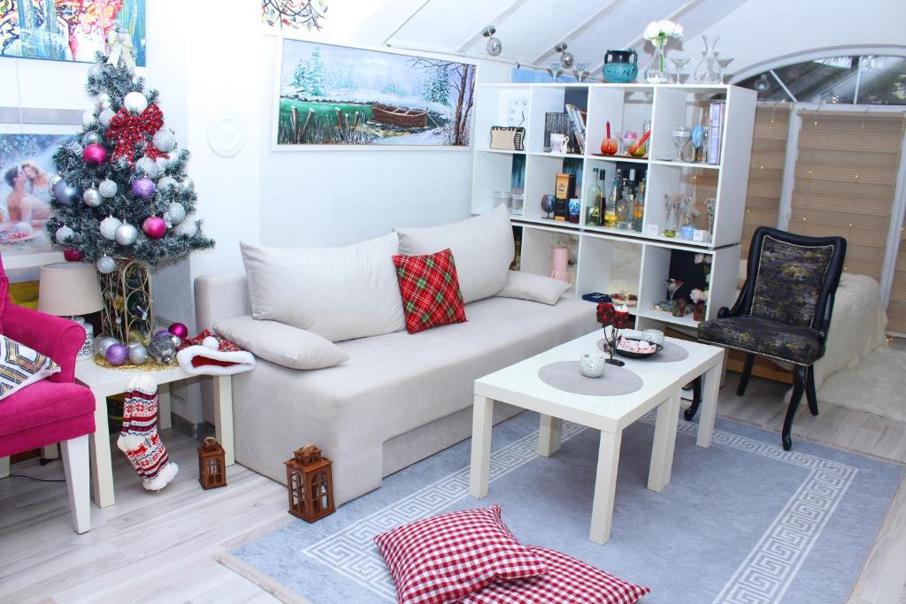a living room with a white couch and a christmas tree at Art apartman in Kakanj