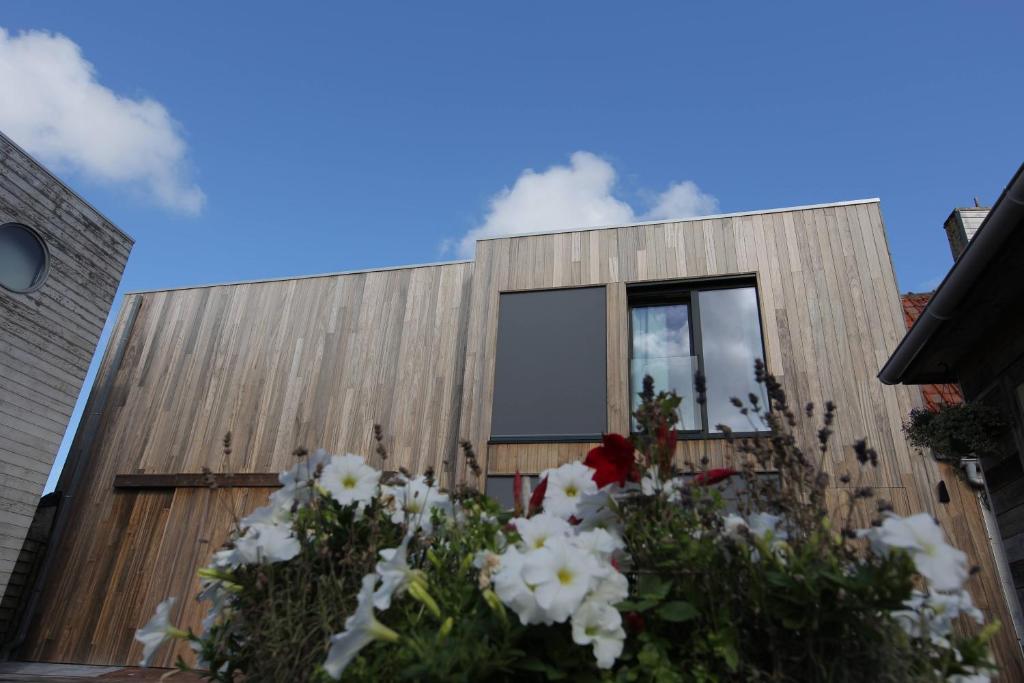 un bâtiment en bois avec des fleurs devant lui dans l'établissement De Panne - Adinkerke - 't Voetbrugsje comfortabele nieuwbouw, à La Panne