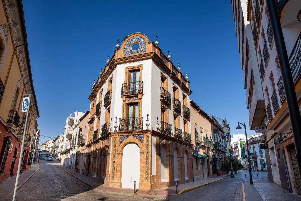 a building with a clock on top of it on a street at Posada Boutique El Gallo Morón in Morón de la Frontera