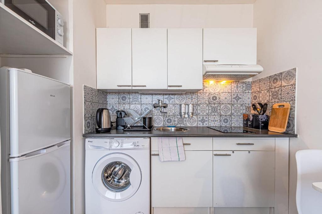 a kitchen with white cabinets and a washer and dryer at L&#39;Horizon in Metz