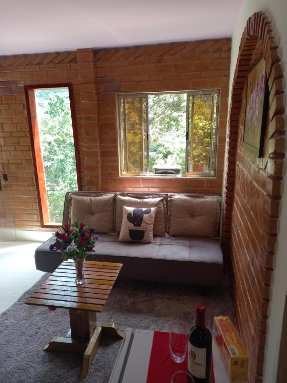 a living room with a couch in a brick wall at Pousada Rancho das Flores in Espera Feliz