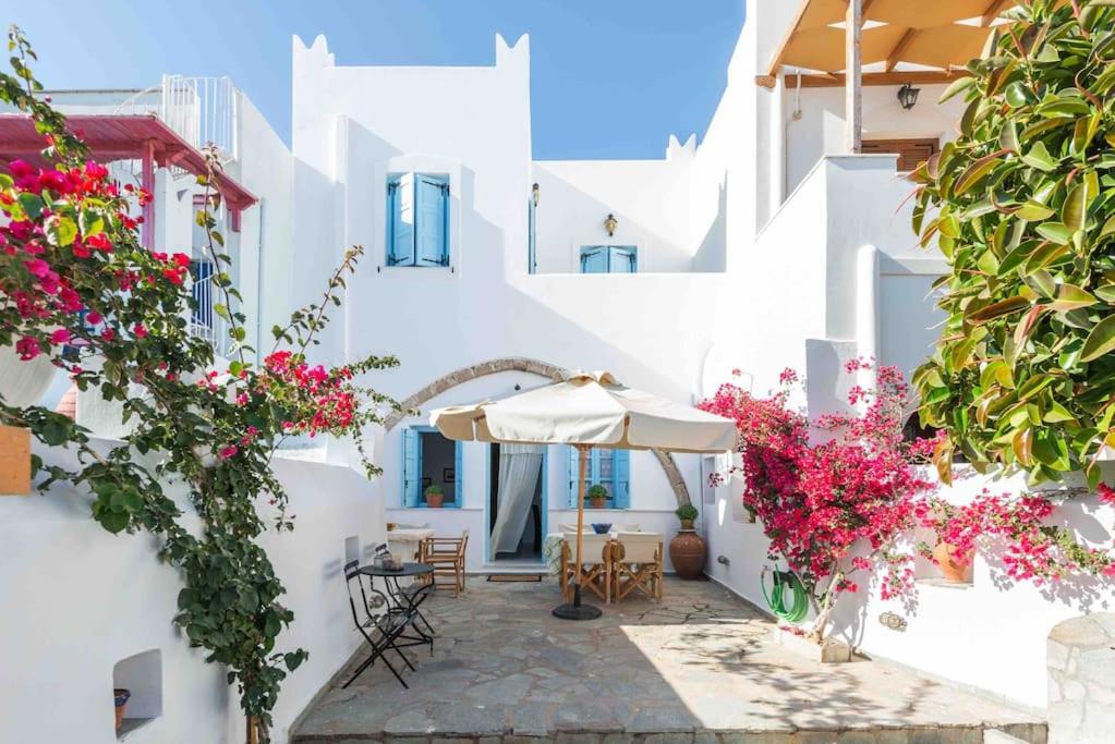 GalanádhonにあるTraditional Two Story House in Galanado Naxosの花と傘が並ぶ屋外パティオ