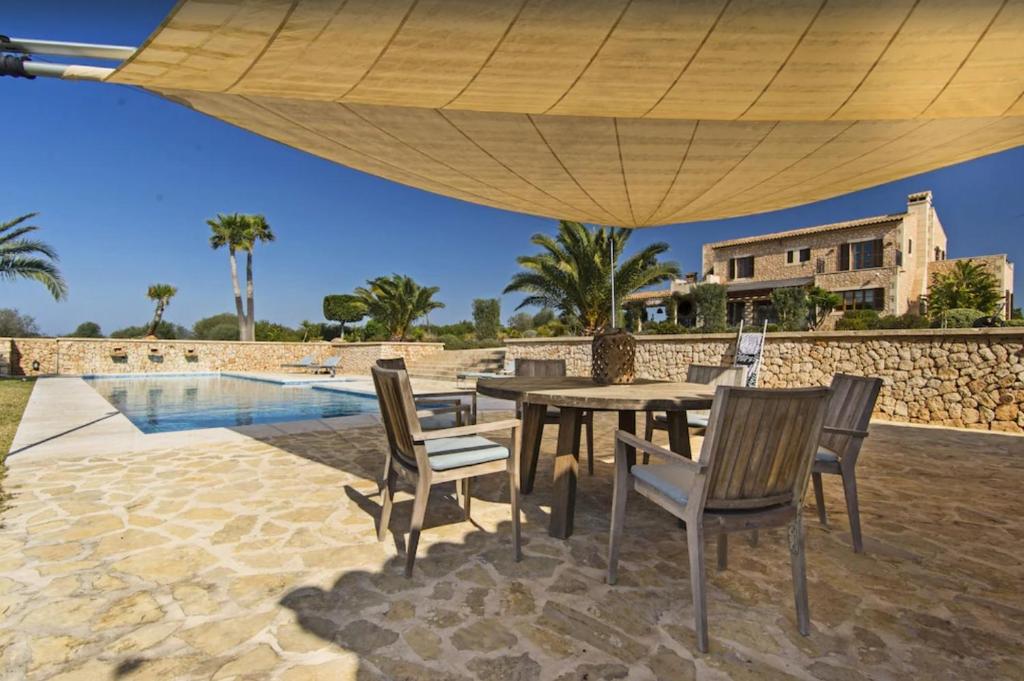 uma mesa e cadeiras debaixo de um guarda-sol ao lado de uma piscina em Finca El Sueno em Santanyi