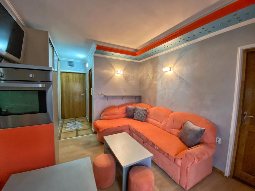 a living room with an orange couch and a tv at Apartman Marko B in Vrnjačka Banja