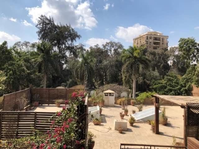 un jardin avec une clôture et des fleurs ainsi qu'un bâtiment dans l'établissement Lovely gorgeous apartment among green Maadi, au Caire