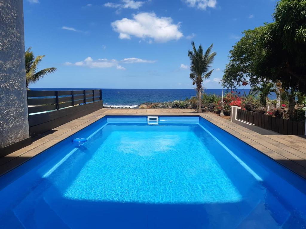 a blue swimming pool with the ocean in the background at La Falaise Sea Front Villa in Flic-en-Flac
