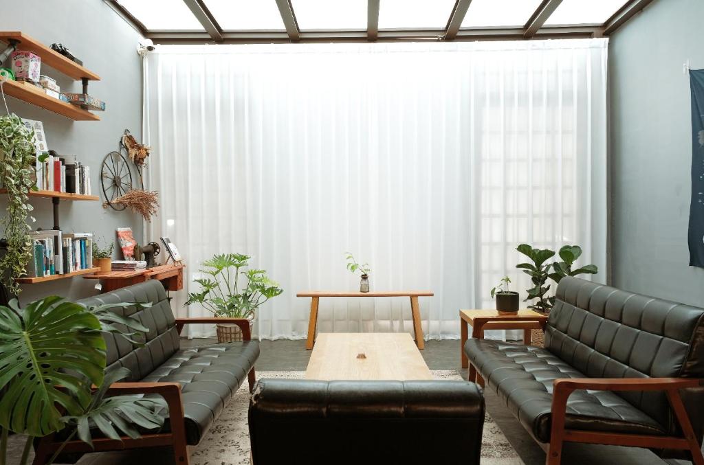 uma sala de estar com sofás de couro e uma mesa em Journey Hostel em Tainan