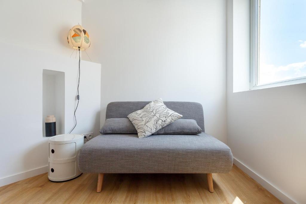 a gray ottoman in a room with a window at Shiro - Appartement 2beapart in Lyon