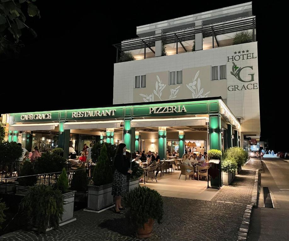 a group of people sitting outside of a restaurant at night at Hotel Grace in Međugorje