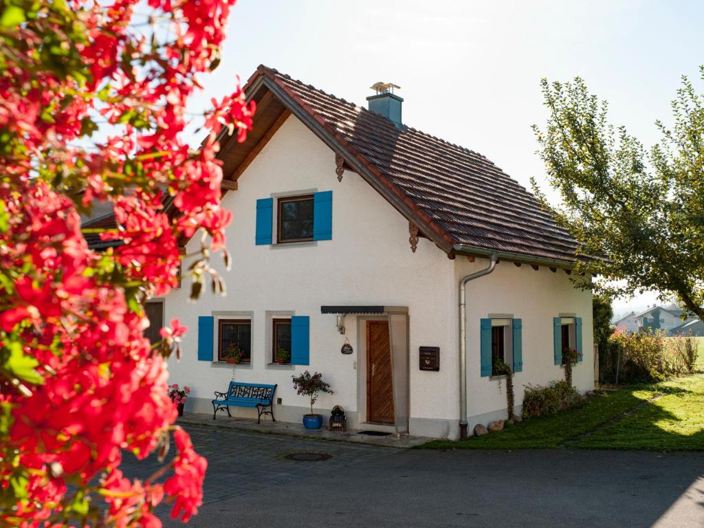ein weißes Haus mit blauen Fenstern und einem Baum in der Unterkunft Ferienhaus Wolferstetter in Tittmoning
