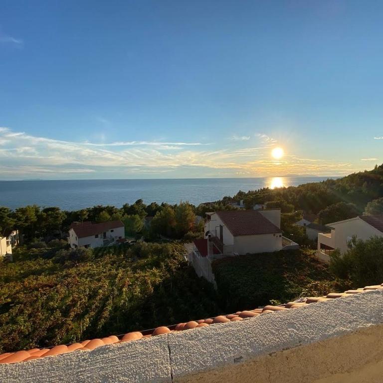 a view of a house with the sun setting over the ocean at Apartmani "Nikola" Seaview - Ivan Dolac, Hvar in Ivan Dolac
