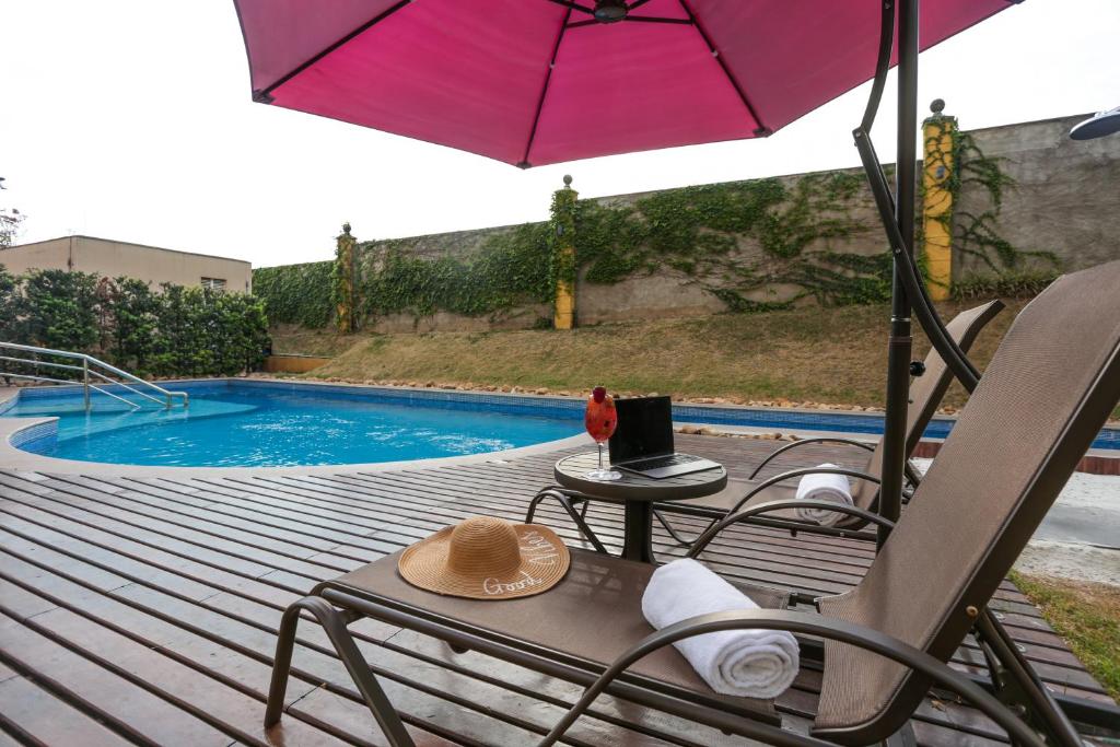 einen Stuhl und einen Regenschirm neben einem Pool in der Unterkunft Intercity Vinhedo in Vinhedo