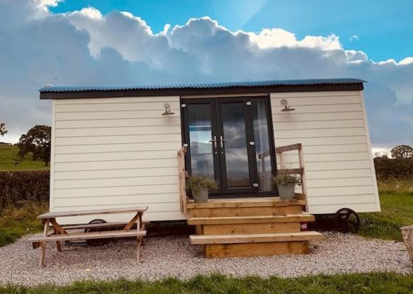 a small white shed with a porch and a bench at Ribble Valley Retreat in Langho