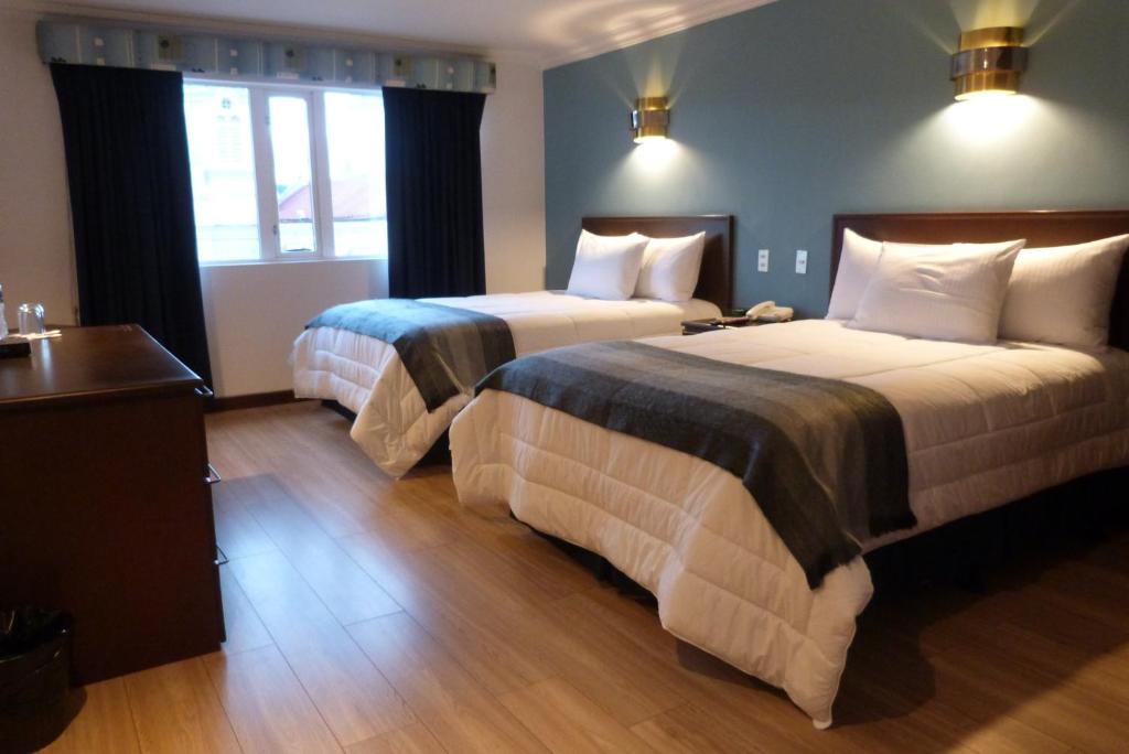 a hotel room with two beds and a window at Hotel El Conquistador in Cuenca