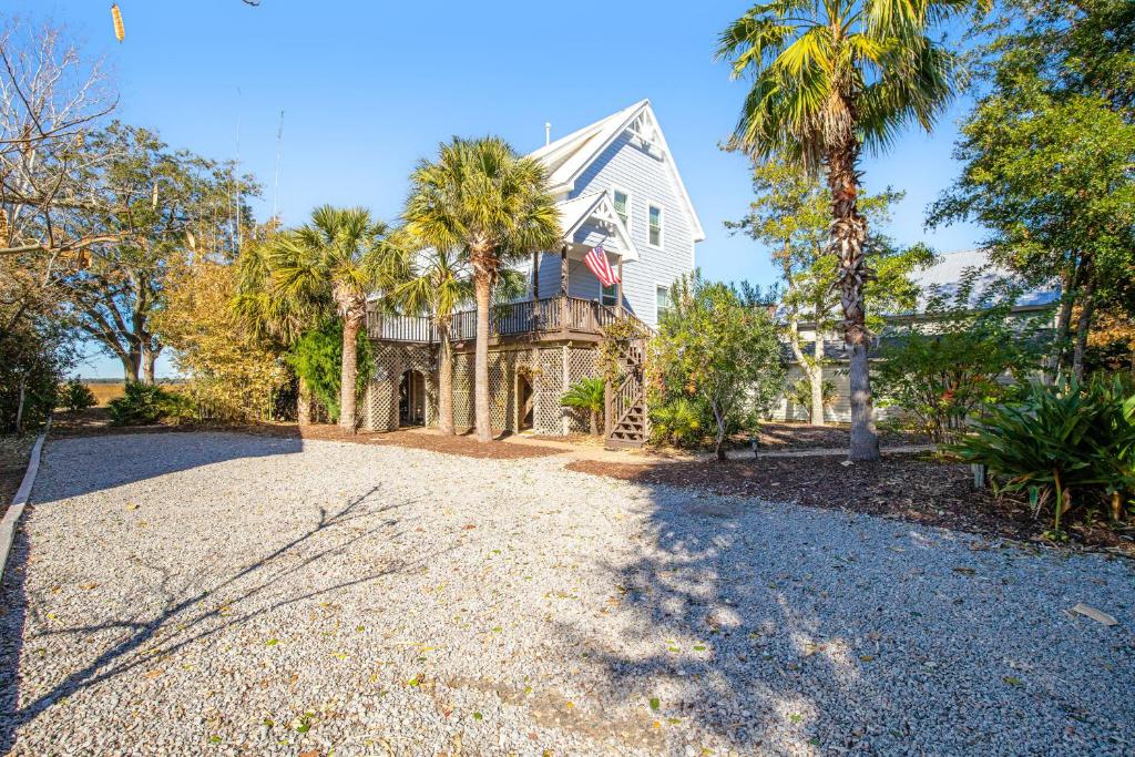 a house with palm trees and a gravel driveway at Pelican's Hideaway in Folly Beach