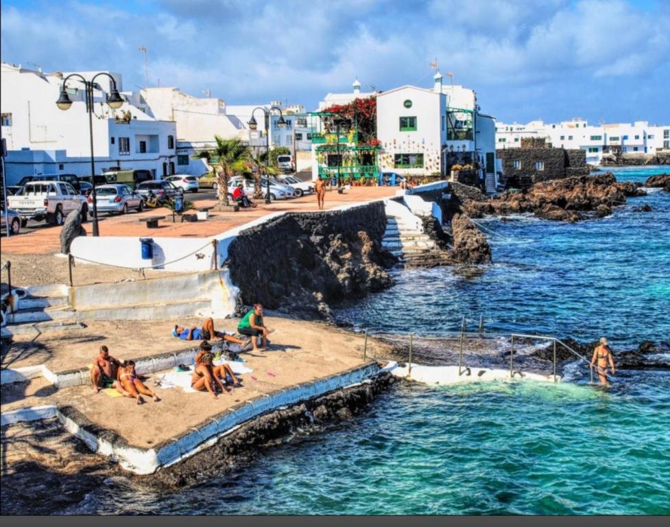 Relaxlanzarote في بونتا موخيريس: مجموعة من الناس يجلسون على شاطئ بجوار الماء