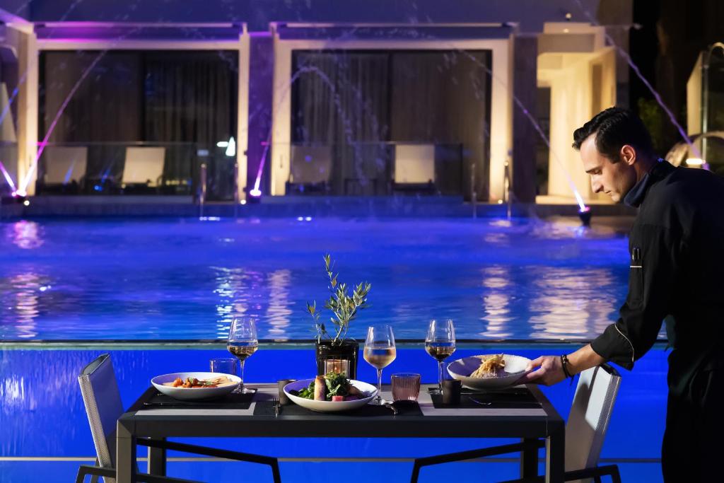 a man standing at a table with food and wine glasses at Akti Toroni Boutique Hotel in Toroni