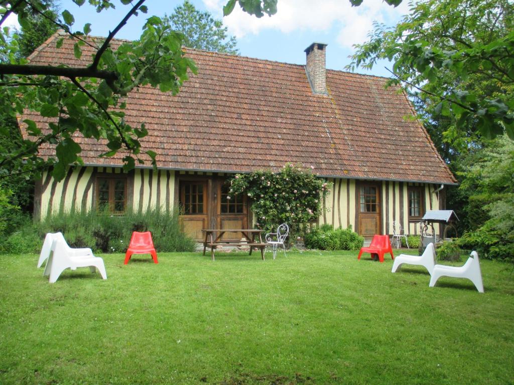 une cour avec des chaises rouges et blanches devant une maison dans l'établissement Moulin de la Génetée, à Saint-Aubin-sur-Scie