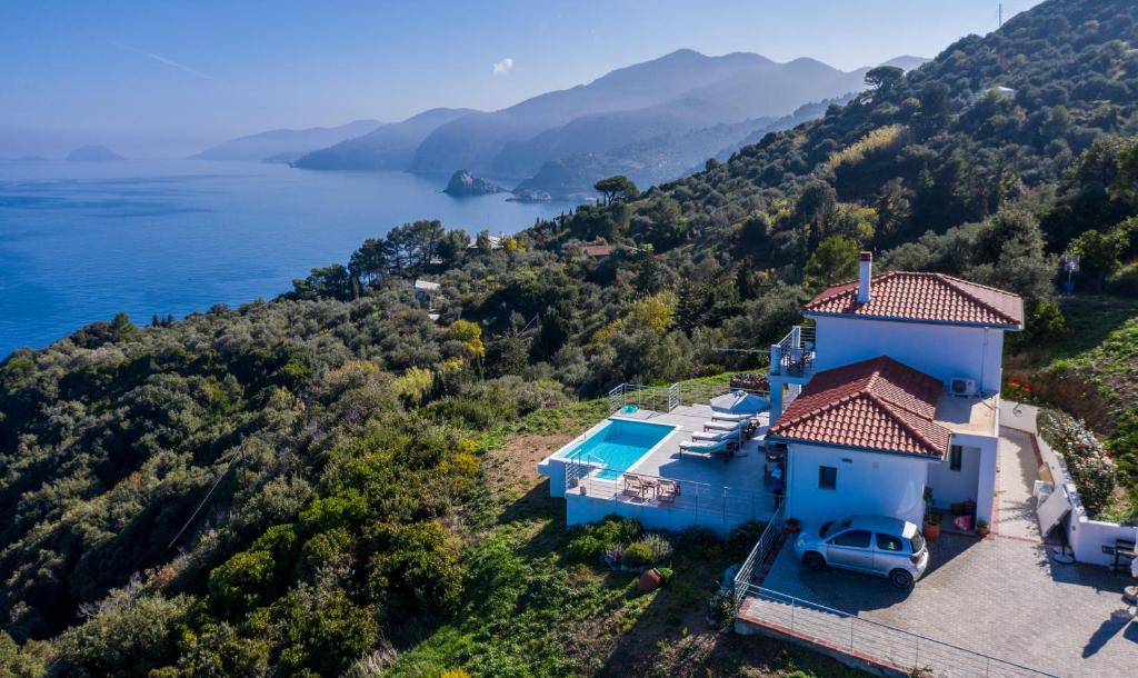 an aerial view of a blue house on a hill next to the water at Mark Heritage in Glóssa