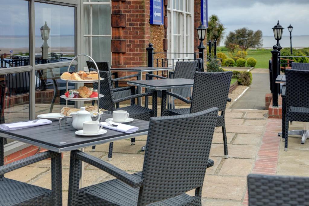 a table and chairs on a patio with food on it at Old Hunstanton Le Strange Arms Hotel in Hunstanton