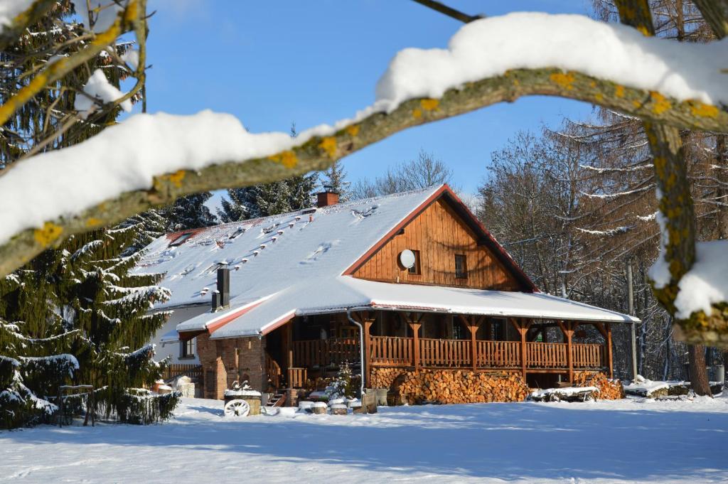 a large wooden cabin with snow on the roof at Penzion Krcma in Dolní Morava