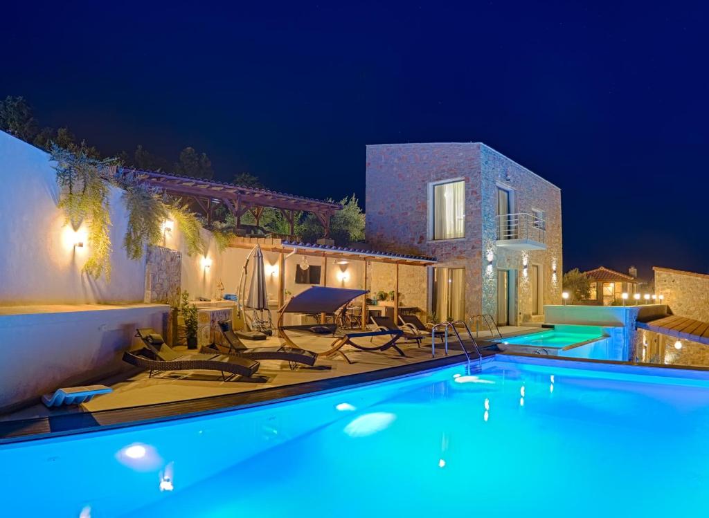 a swimming pool with chairs and a house at night at Sky Sea Resort Skiathos in Skiathos Town