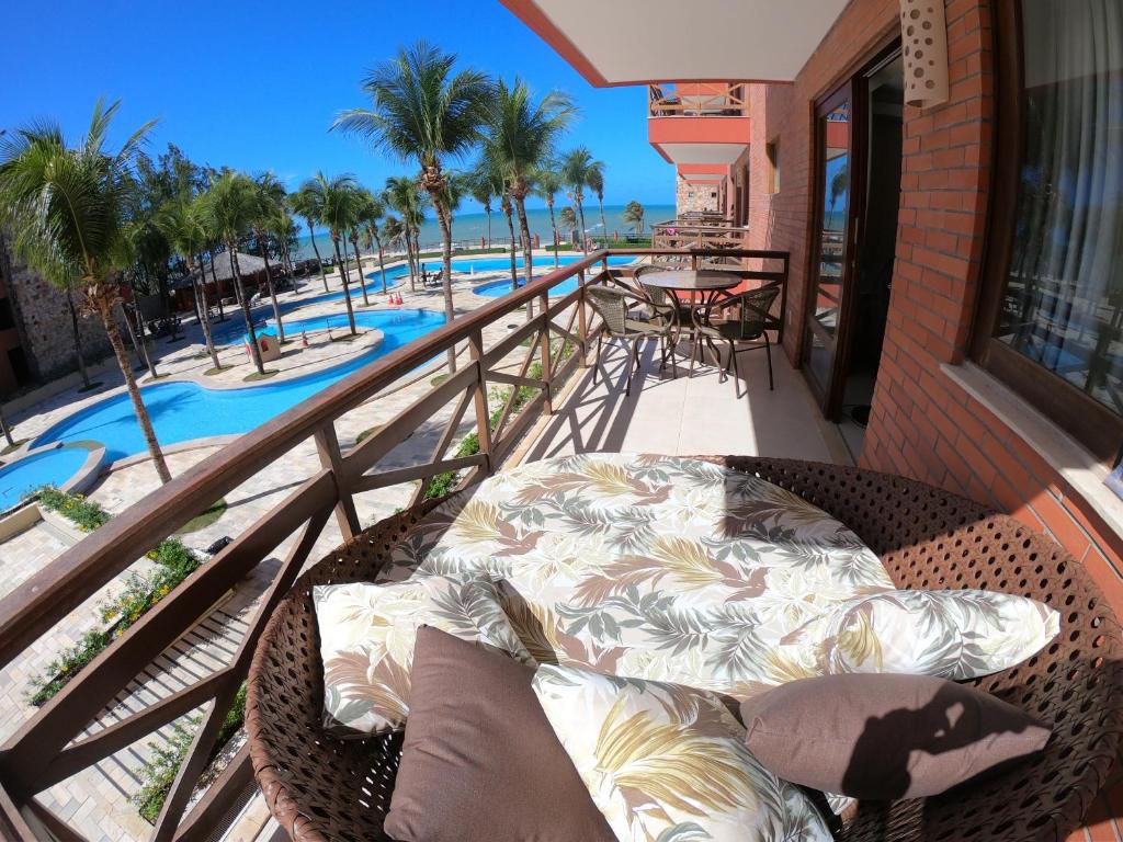 uma cama de vime numa varanda ao lado de uma piscina em [Kariri 215] 46m², pé na areia, varanda vista mar! em Cumbuco