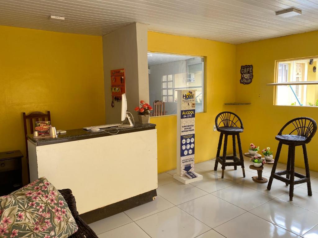a kitchen with yellow walls and two stools in a room at Pousada Do Sol in Parnaíba