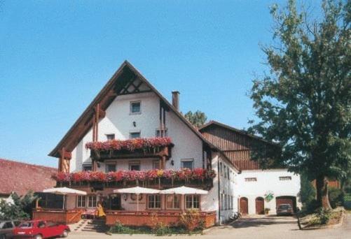 - un grand bâtiment blanc avec des fleurs rouges dans l'établissement Gasthaus zur Traube, à Winterrieden