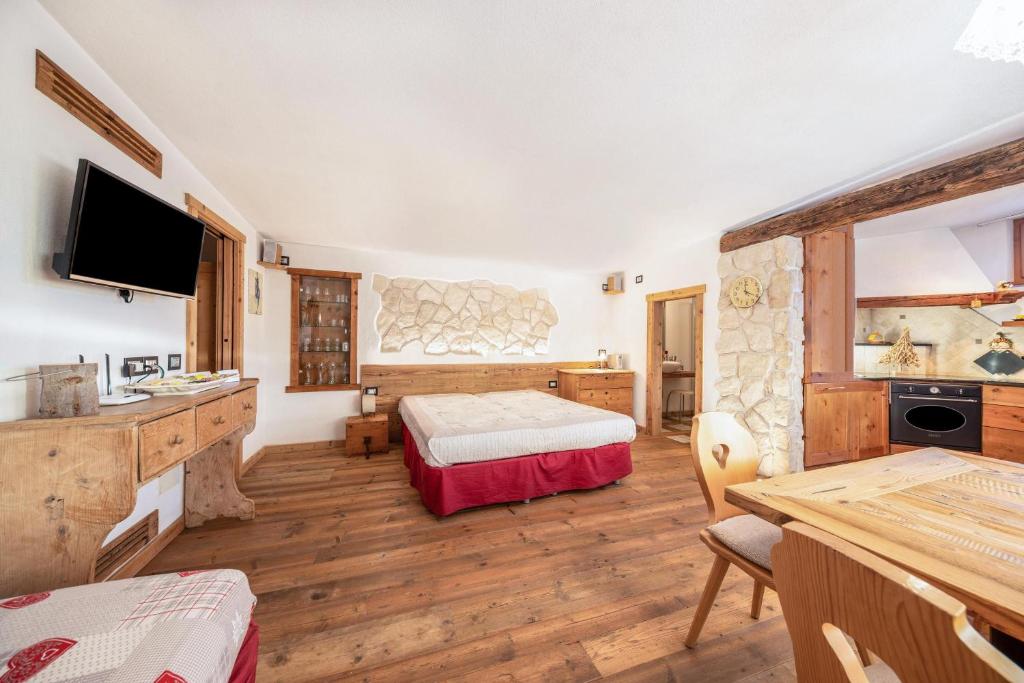 ein Schlafzimmer mit einem Bett und einem TV in einem Zimmer in der Unterkunft La pratolina monolocale in Castello di Fiemme