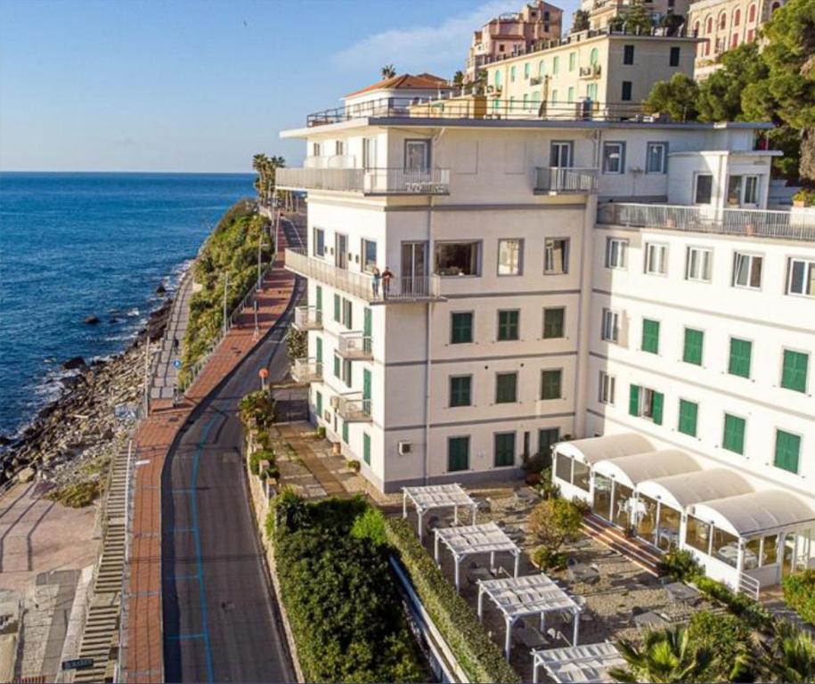 un grande edificio bianco vicino all'oceano di Hotel Corallo a Imperia