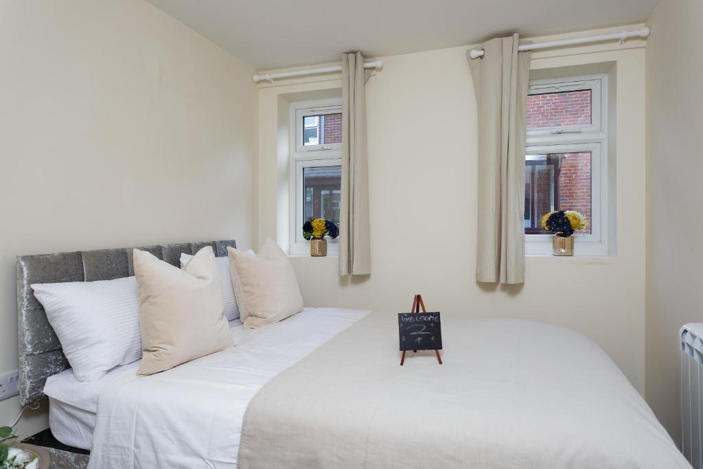 una camera da letto con un grande letto bianco con cuscini bianchi di Luxury Burgess Apartments close to Soton General Hospital a Southampton