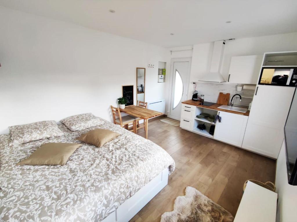 um quarto branco com uma cama e uma cozinha em Studio cosy Bienvenue chez Elle em Saint-Denis-de lʼHôtel