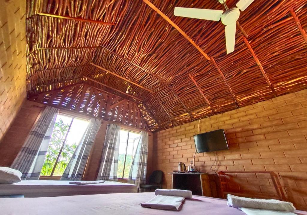 een kamer met 2 bedden en een groot raam bij Cinnamon Village Sinharaja in Deniyaya