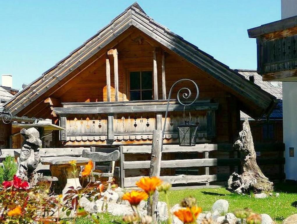 una pequeña casa de madera con flores delante en Haus Andreas - Chalet 306, en Turracher Höhe