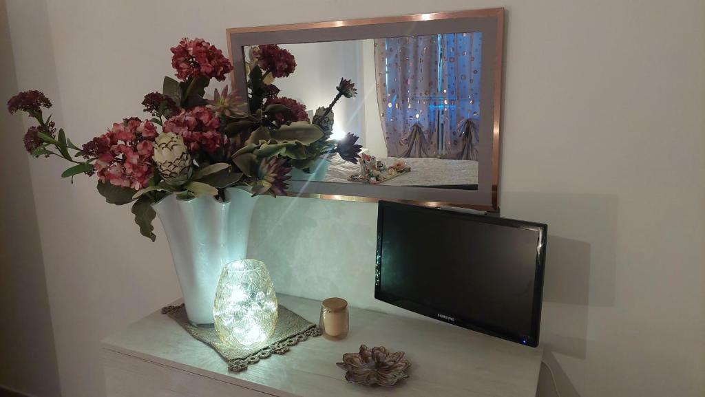 telewizor siedzący na stole z wazą z kwiatami w obiekcie Sweet Home w mieście Lido di Ostia