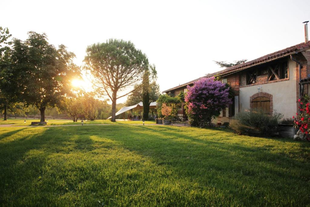 a grassy yard next to a house with the sun setting at Chambre d'hôtes Belair in Muret