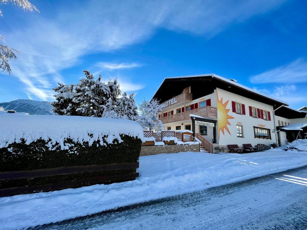 a building with snow on the side of a street at Hotel AlpenSonne Ruhpolding in Ruhpolding