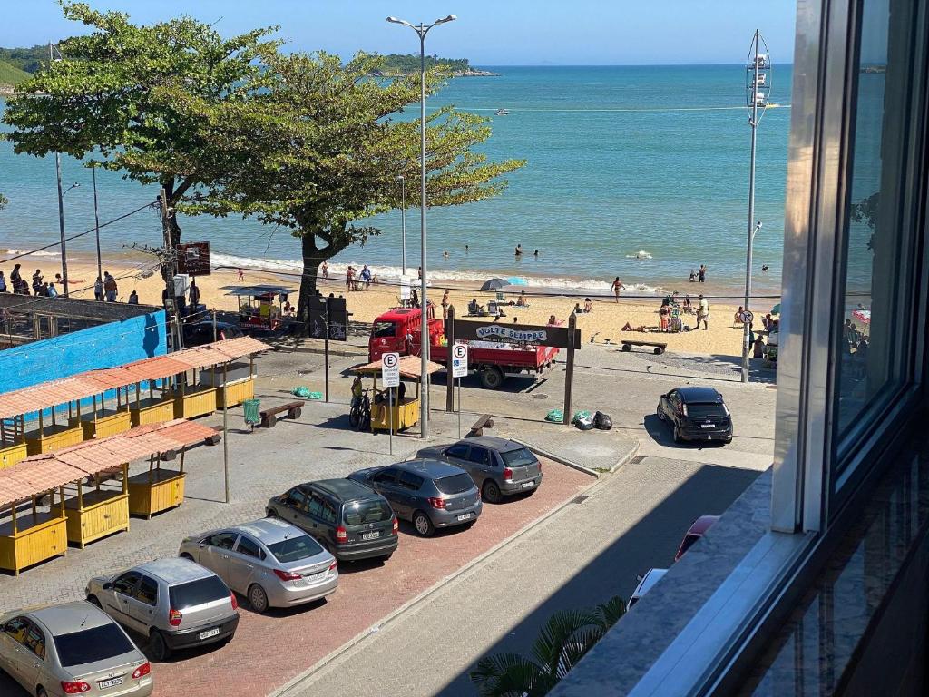 uma vista para uma praia com carros estacionados num parque de estacionamento em Apto a beira mar no Centro - WIFI 200MB - TV Smart - Cozinha equipada - Portaria 24h - Ar condicionado em Rio das Ostras
