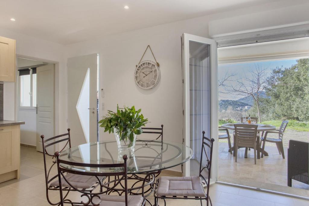 uma cozinha e sala de jantar com uma mesa de vidro e cadeiras em Domaine Ghjulia em Patrimonio