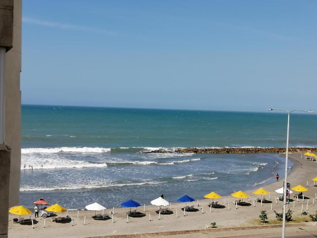 einen Strand mit Liegestühlen und Sonnenschirmen und dem Meer in der Unterkunft Apartamento mar in Cartagena de Indias