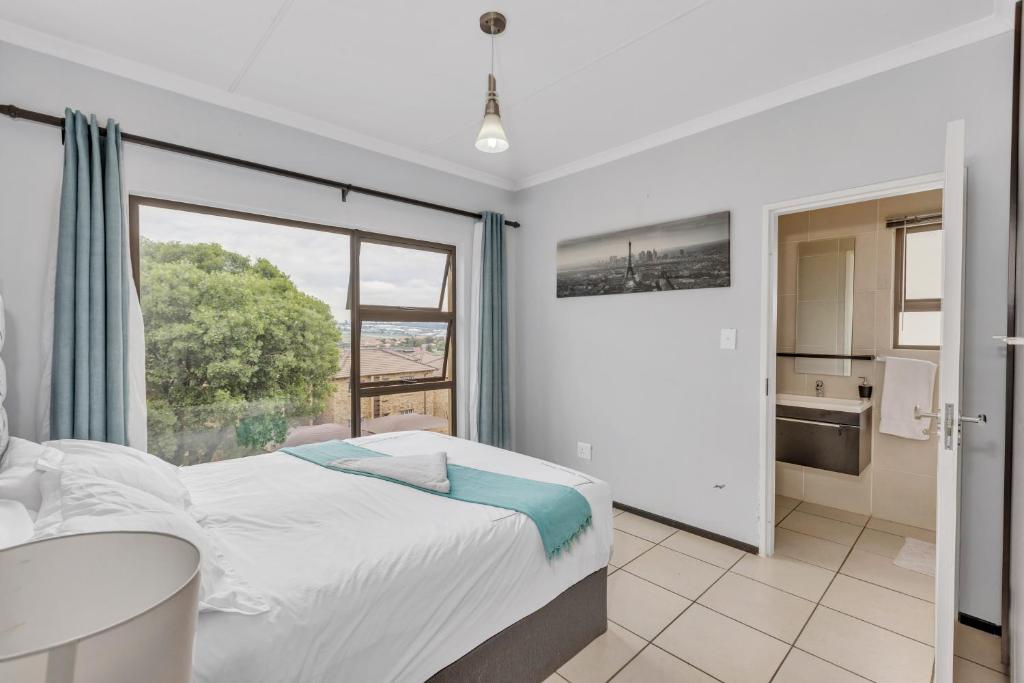 a bedroom with a bed and a large window at Smartz Apartment 76 in Midrand